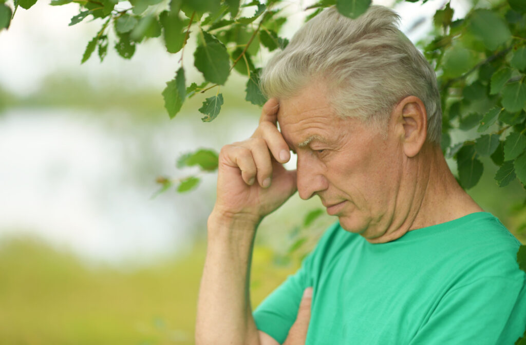 A senior person wearing a green shirt looking confused after wandering outdoors.