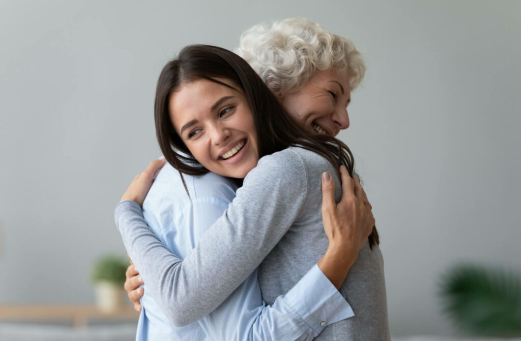 A happy young woman and a happy senior woman hugging each other.