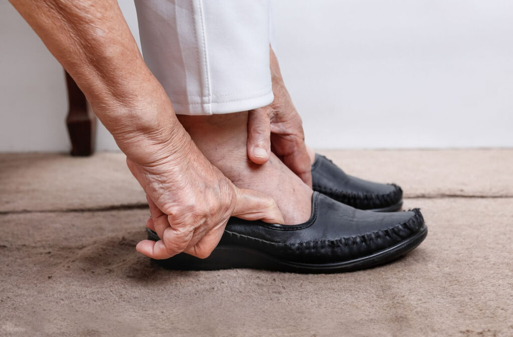 An older adult woman putting on a pair of slip-on shoes.