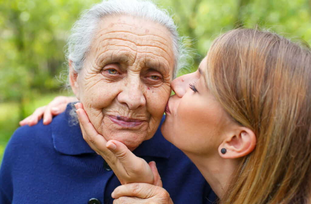 A woman kissing her mother on the cheek in a park